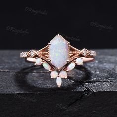 an opal and diamond ring on top of a black surface