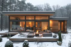 a modern cabin in the snow with outdoor furniture