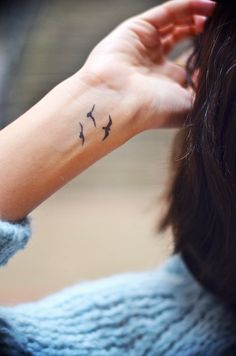 a woman's hand with a small bird tattoo on it