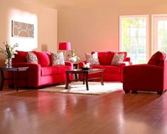 a living room filled with red couches and pillows on top of a hard wood floor