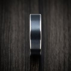 a black and silver wedding ring on a wooden surface