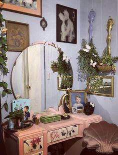 there is a vanity with flowers and pictures on the wall next to it in this room