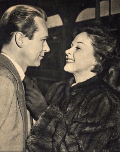 an old black and white photo of a man and woman smiling at each other,