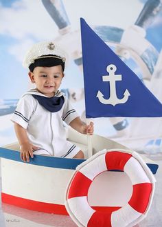 a little boy sitting in a toy boat with an anchor and life preserver on it