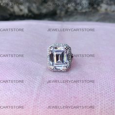 an emerald cut diamond surrounded by diamonds on a pink surface with the names below it