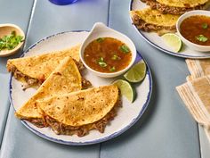 two plates with quesadillas and salsa on them, along with bowls of soup