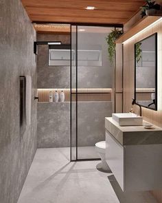 a bathroom with a sink, toilet and shower in it's center wall is lit by recessing lights