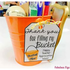 an orange bucket filled with office supplies and a thank you for filling my bucket sign