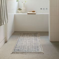 a bathroom with a rug on the floor next to a bathtub and shower curtain