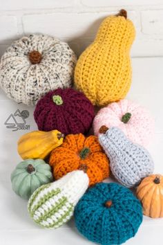 crocheted pumpkins and gourds are arranged on a white table top