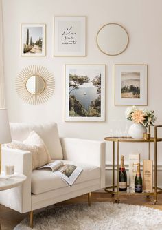 a living room filled with white furniture and pictures on the wall above it's coffee table