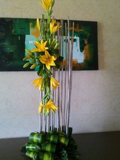 a vase filled with yellow flowers sitting on top of a table next to a painting