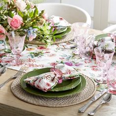 the table is set with pink flowers and green plates