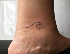 a small wave tattoo on the ankle