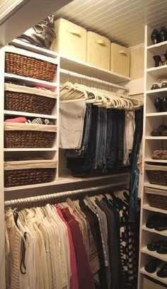 an organized closet with clothes, shoes and baskets on the shelves in front of it