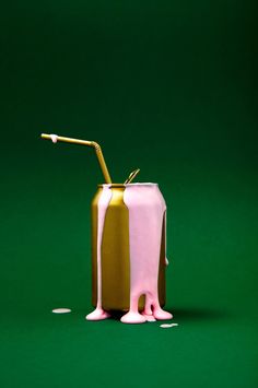 a pink and gold drink sitting on top of a green table next to a straw