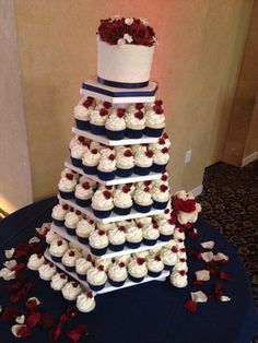 a three tiered wedding cake with cupcakes on the bottom and red roses on top