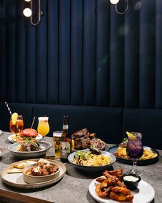 a table topped with plates of food next to bottles of alcohol and glasses filled with drinks