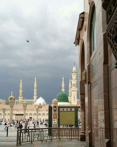 people are walking around in front of an ornate building with green domes and minarets