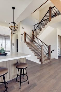 a kitchen with two stools next to a counter and stairs in the middle of it