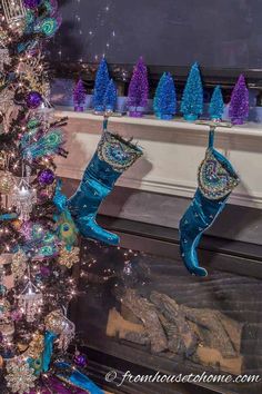 christmas tree with blue boots and decorations in front of fireplace text reads how to decorate a christmas mantle with a tv above it