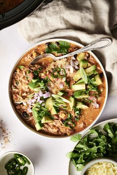 a bowl of chicken tortilla soup with avocado and cilantro