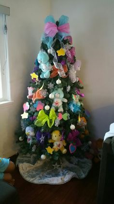 a brightly colored christmas tree in the corner of a room with stuffed animals on it