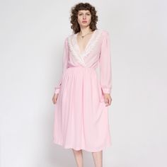 Vintage 70s/80s baby pink long sleeve midi dress with a wrap cut bodice with lace trim, and a fitted elastic waist. It has shoulder pads which can be easily removed with a seam ripper if desired. Measurements and Condition: Fits like: Women's medium Fabric: Feels like polyester, semi-sheer (skirt is lined) Brand: Coco of California Condition: Very good, with light general wear, some very faint light discoloration in the underarms, a few tiny faint speckled brown spots on the cuff buttons, and so Spring Vintage Midi Dress With Lace Trim, Vintage Midi Dress With Lace Trim For Spring, Spring Midi Dress With Long Sleeves And Lace Trim, Feminine Midi Dress With Surplice Neckline For Daywear, Vintage Lace Trim Midi Dress For Spring, Vintage Dress With Lace Long Sleeves, Spring Pink Midi Dress With Surplice Neckline, Vintage Long Sleeve Midi Dress For Daywear, Pink Midi Dress With Surplice Neckline For Spring