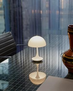 a lamp sitting on top of a glass table next to a vase with a flower in it