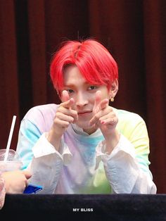 a woman with red hair sitting in front of a laptop and holding her hands up