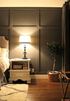 an image of a bedroom with gray walls and white furniture, including a lamp on the end table