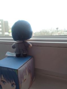 a small stuffed animal sitting on top of a box next to a window sill