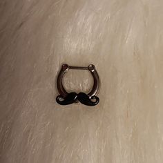 a metal nose ring with a black handle on top of a white fur covered surface