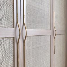 a white closet with gold handles and mesh doors