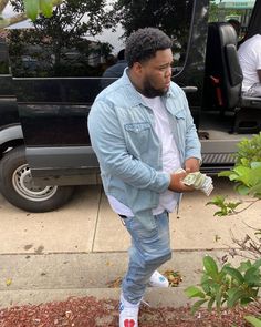 a man standing in front of a van holding money