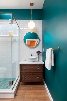 a bathroom with blue walls and white tile on the floor, along with a wooden vanity topped with a round mirror