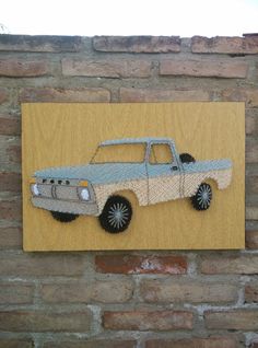 a paper cut out of a pickup truck on a wooden plaque mounted to a brick wall