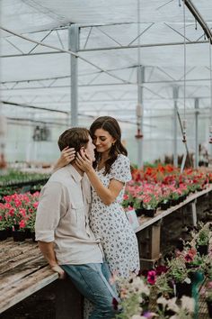 a man and woman kissing in a greenhouse