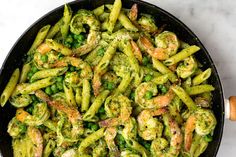 a skillet filled with green pasta and shrimp