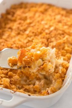 a casserole dish filled with macaroni and cheese being held by a spoon