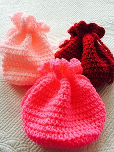 three crocheted hats sitting on top of a bed