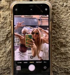 a cell phone with an image of two people on the screen and one person taking a selfie