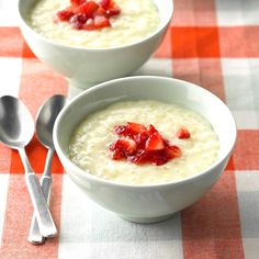 two bowls of oatmeal with strawberries in them on a checkered tablecloth