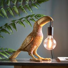 a bird figurine sitting on top of a table next to a light bulb