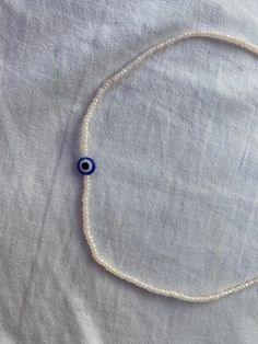 a handmade necklace that is filled with white beads with 1 evil eye bead on it. White Evil Eye, Old Bridge, Beaded Necklaces, White Beads, Handmade Necklace, How To Make Beads, Chain Styles, Handmade Necklaces, Evil Eye