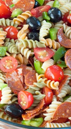 pasta salad with pepperoni, olives, tomatoes and peppers in a glass bowl