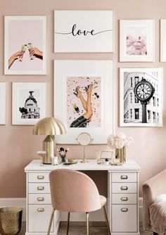 a white desk topped with a pink chair next to a wall covered in framed pictures