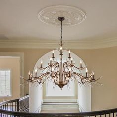 a chandelier hanging from the ceiling in a room with white walls and stairs