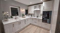 a large kitchen with white cabinets and wood flooring on the walls, along with an oven in the center