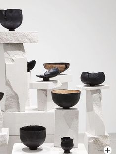 black and white bowls are stacked on top of each other in front of a white wall